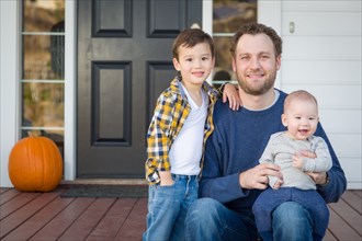 Young mixed-race father and sons on front porch