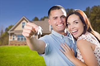 mixed-race excited military couple in front of new home showing off their house keys