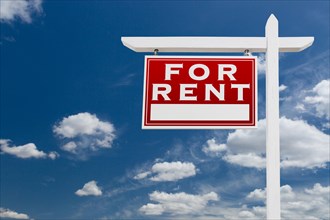Left facing for rent real estate sign over blue sky and clouds with room for your text