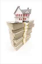 Small house on stacks of hundred dollar bills isolated on a white background