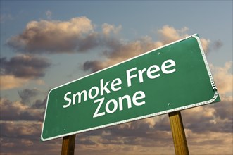 Smoke free zone green road sign in front of dramatic clouds and sky