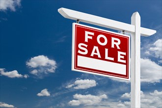 Left facing for sale real estate sign over blue sky and clouds with room for your text