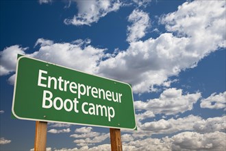 Entrepreneur boot camp green road sign and dramatic clouds background