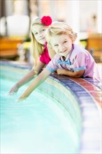 Cute young caucasian brother and sister enjoying the fountain at the park