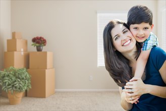 Young mother and son inside empty room with moving boxes