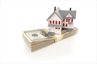 Small house on stack of hundred dollar bills isolated on a white background