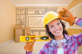 Female construction worker holding level in front of custom built in entertainment unit drawing in empty room