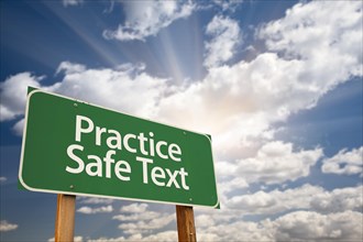 Practice safe text green road sign with dramatic sky
