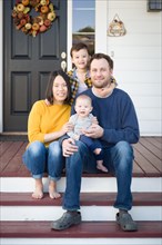 Young mixed-race chinese and caucasian family portrait on their front porch