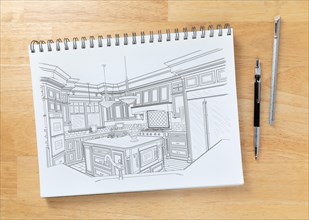 Sketch pad on desk top with drawing of custom kitchen interior next to engineering pencil and ruler scale