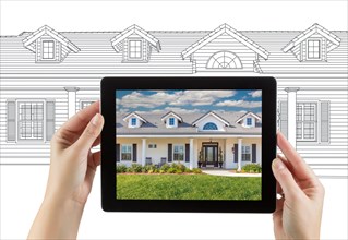 Female hands holding computer tablet with house photo on screen & drawing behind
