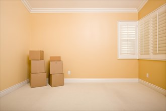 Moving boxes in empty room with copy space on blank wall