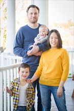 Young mixed-race chinese and caucasian family portrait on their front porch