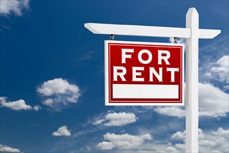 Left facing for rent real estate sign over blue sky and clouds with room for your text