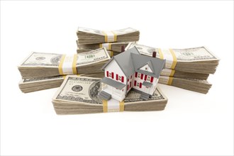 Small house with stacks of hundred dollar bills isolated on a white background