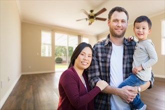 mixed-race chinese and caucasian parents and child inside empty room of new house