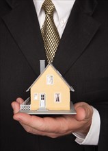 Businessman with coat and tie holding house