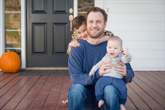 Young mixed-race father and sons on front porch