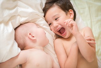 Young mixed-race chinese and caucasian baby brothers having fun on their blanket