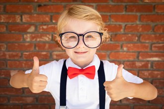 Cute young caucasian boy with thumbs up wearing glasses and red