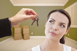 Attractive young woman being handed the keys in empty green room with boxes