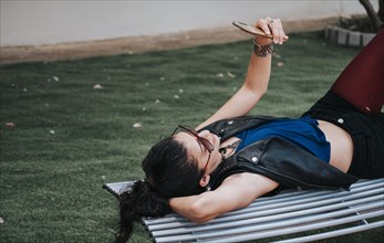 A girl lying on a bench with her cell phone