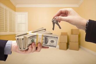 Man and woman handing over cash for house keys inside empty room with boxes