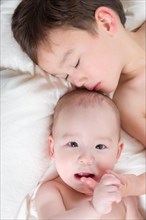 Young mixed-race chinese and caucasian baby brothers having fun on their blanket