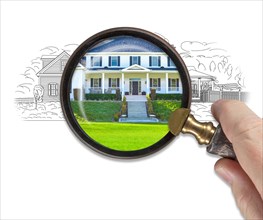 Hand holding magnifying glass revealing finished house build over drawing