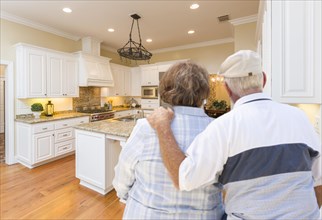 Happy senior couple looking over beautiful custom kitchen design