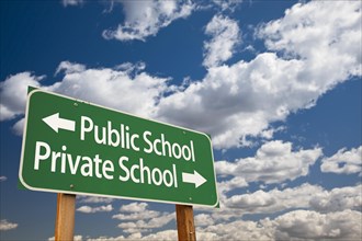 Public or private school green road sign over dramatic clouds and sky