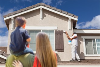 Young family watching home get painted by house painter
