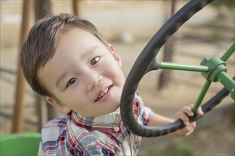 Adorable mixed-race young boy playing on the tractor at the pumpkin patch