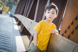Handsome mixed-race boy leaning on bridge outdoors