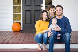 Young mixed-race chinese and caucasian family portrait on their front porch