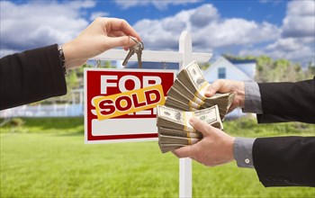 Man handing woman thousands of dollars for keys in front of house and sold for sale real estate sign