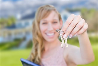 Excited woman holding house keys in front of nice new home