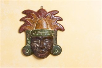 Ornate myan mask hanging on a light yellow wall