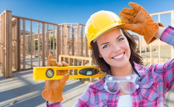 Female construction worker holding level wearing gloves