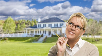 Thinking young woman with pencil in front of beautiful house
