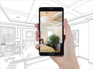 Hand holding smart phone displaying photo of custom bedroom drawing behind