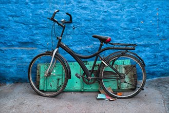 Old bicycle at the wall of blue house in streets of of Jodhpur