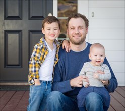 Young mixed-race father and sons on front porch