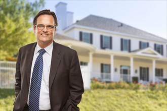Attractive businessman in front of beautiful new residential home