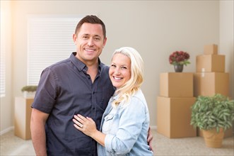 Happy couple inside empty room with boxes