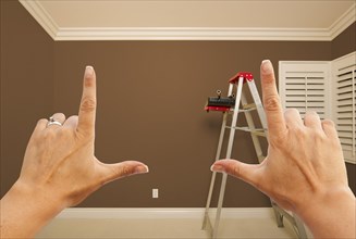 Hands framing brown painted room wall interior with ladder