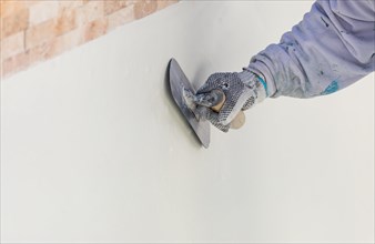 Worker smoothing wet pool plaster with trowel