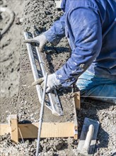 Pool construction worker working with A smoother rod on wet concrete