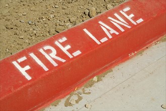 Close-up of red painted curb with fire lane text