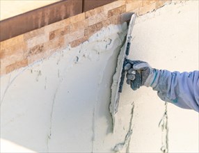 Worker smoothing wet pool plaster with trowel